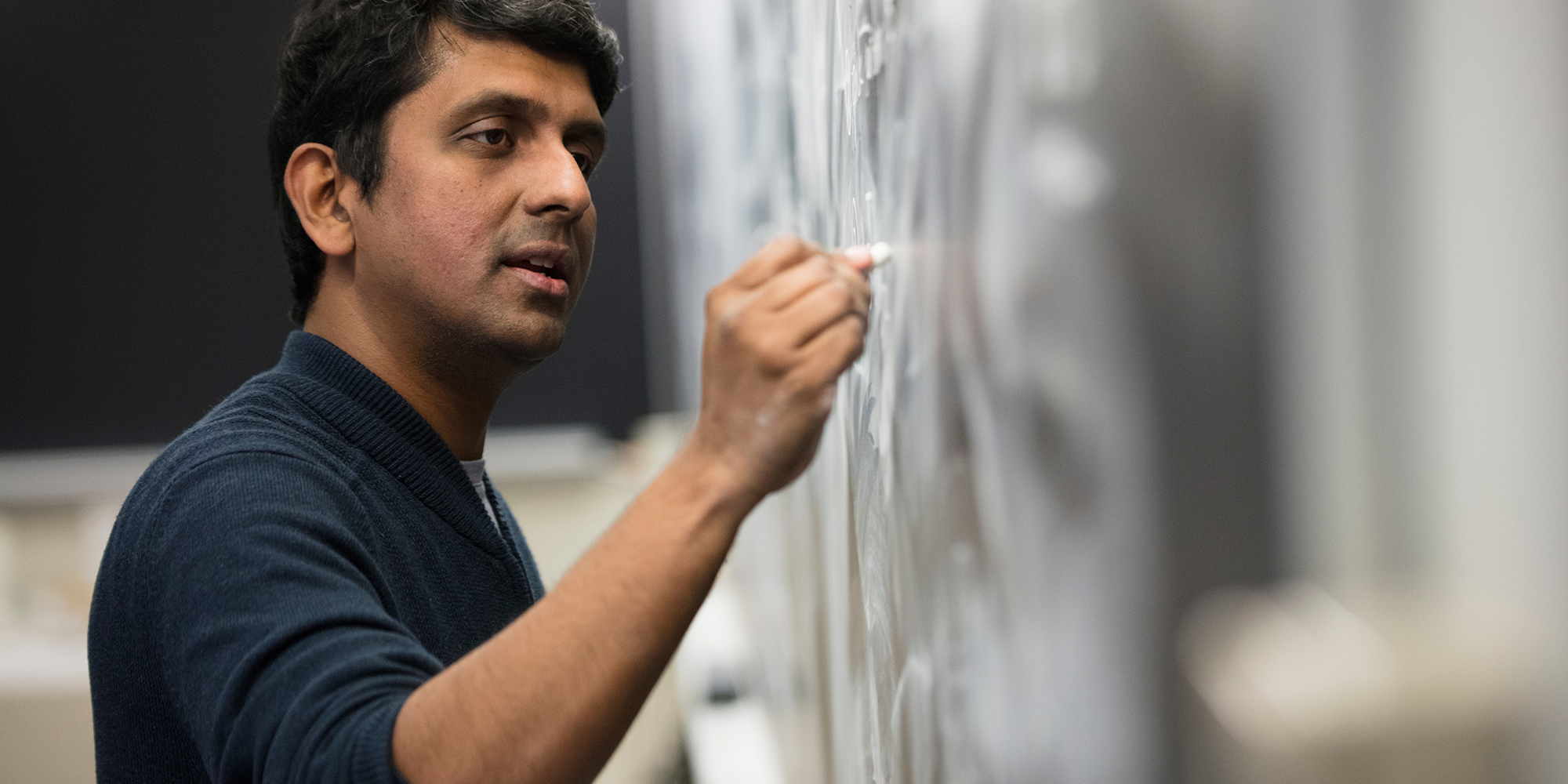 Vinod Vaikuntanathan writing on chalkboard