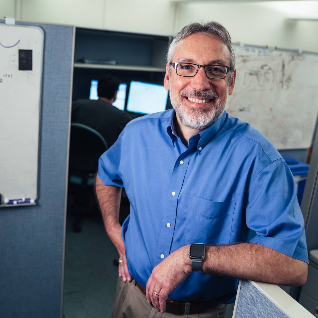 photo of Duane Boning standing in front of cubicles in lab