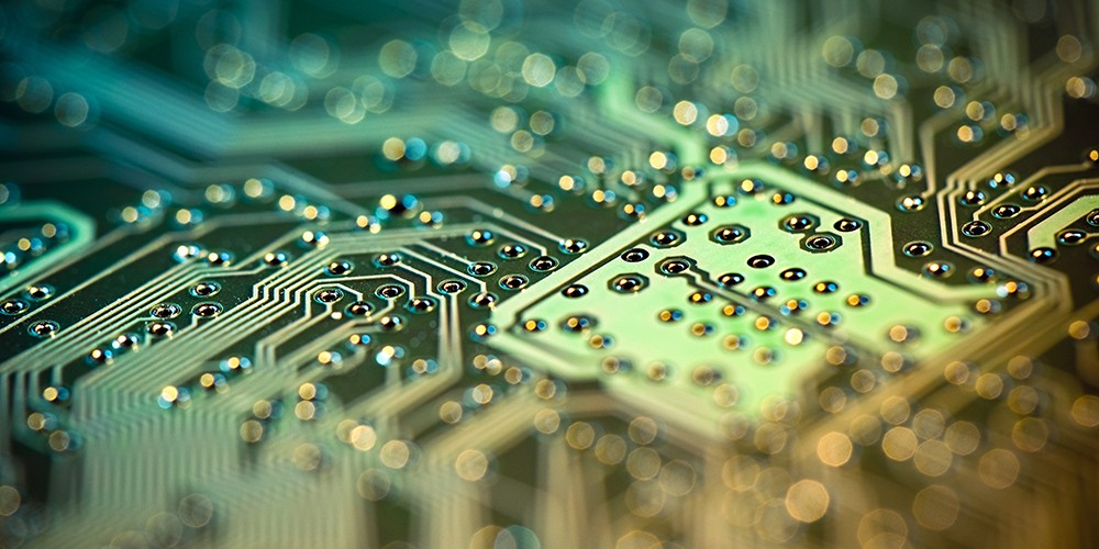 A macro shot of a circuit board in shades of green and yellow with a shallow depth of field