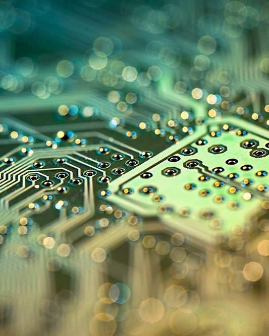 A macro shot of a circuit board in shades of green and yellow with a shallow depth of field