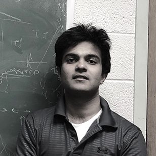 black and white image of Anand standing in front of chalkboard