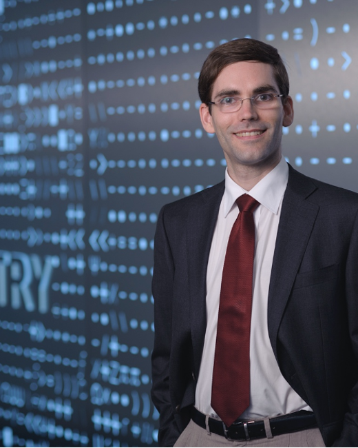 tomas palacios standing in front of blue wall with pattern of numerical symbols