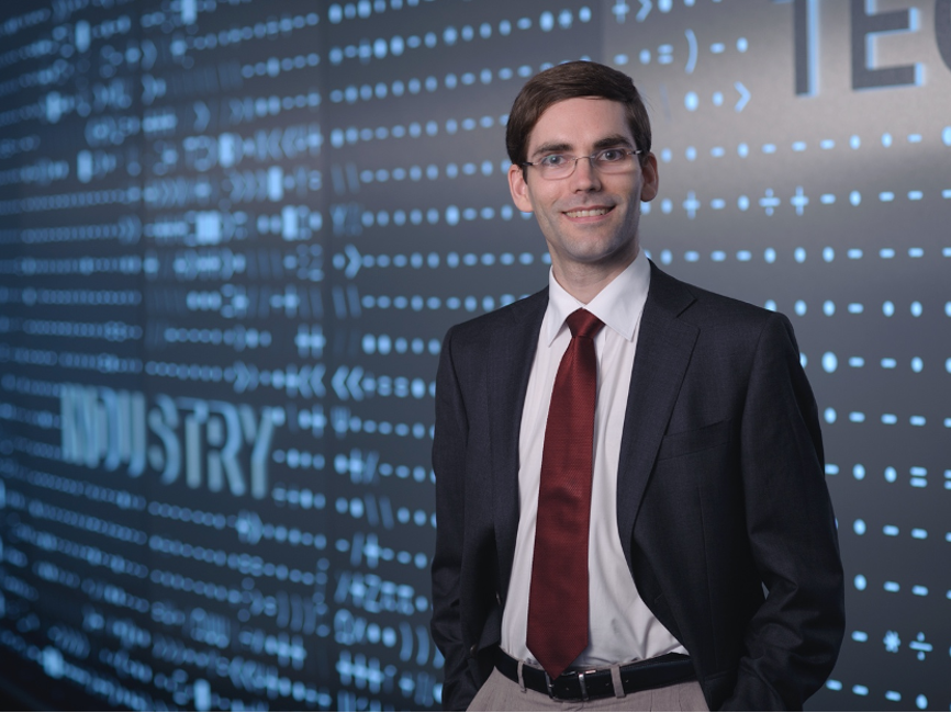 tomas palacios standing in front of blue wall with pattern of numerical symbols