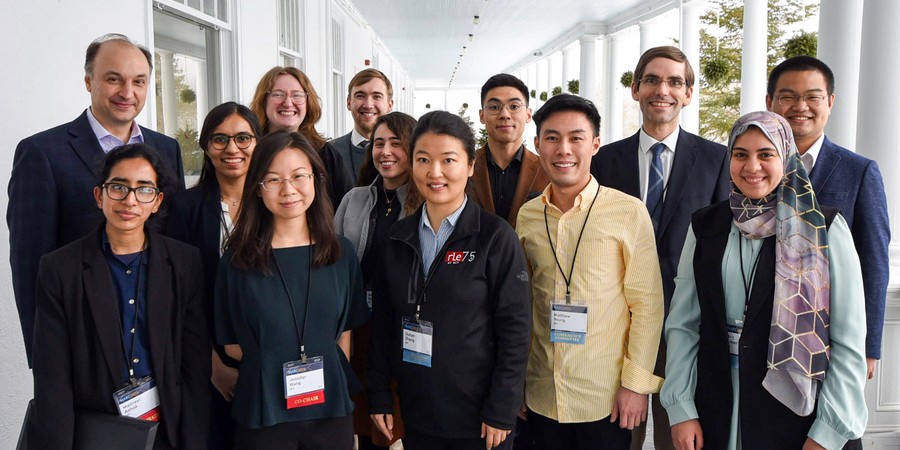 13 people in business attire pose for a group photo on a large, white covered porch