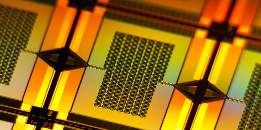 A yellow-lit closeup zooms in on one tiny, rectangular amplifier on the wafer. It has a chain-like rectangular grid in center that connects to the left and right edges of the wafer.
