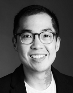 black and white photo of darius wearing glasses and a white shirt with dark jacket