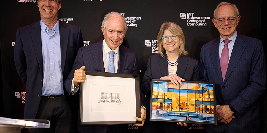 Dan Huttenlocher, Stephen Schwarzman, Sally Kornbluth, and L. Rafael Reif stand against a backdrop featuring the MIT Schwarzman College of Computing logo. Kornbluth holds a framed photo of a glass building, while Schwarzman holds a framed pencil drawing of the same building.