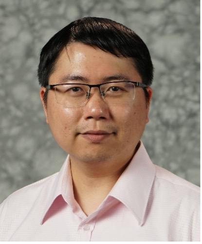 male with classes wearing light color collared shirt in front of speckled grey background