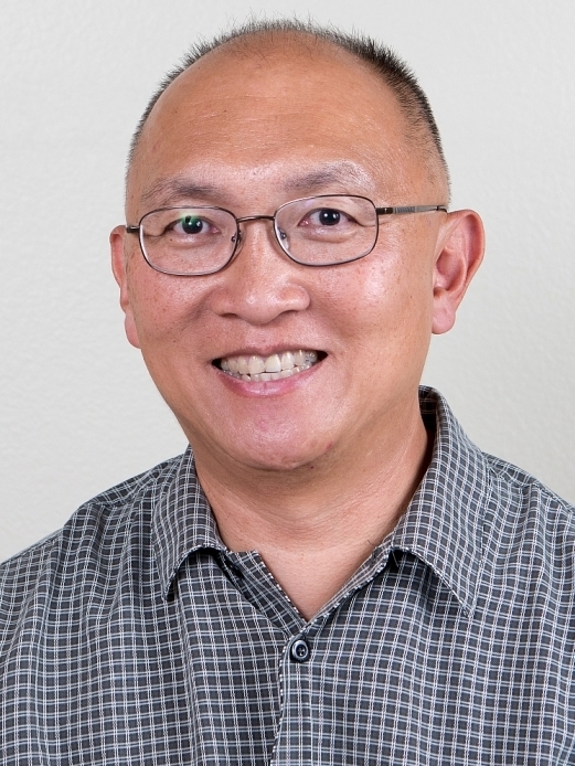 man wearing glasses and collared shirt in front of grey background