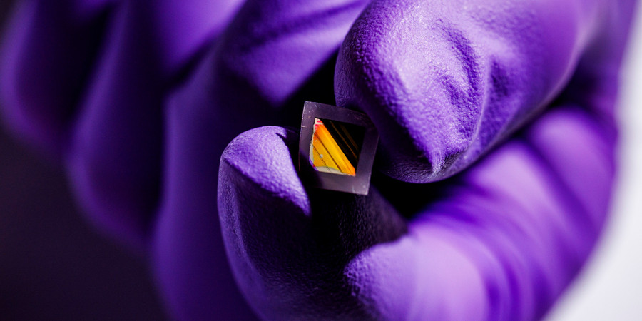 hand with purple medical gloves holding small diamond shape thin film material